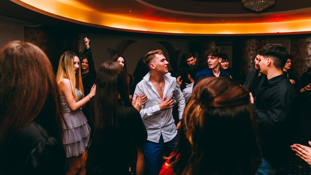 A full room of people gathered around a table during a party game