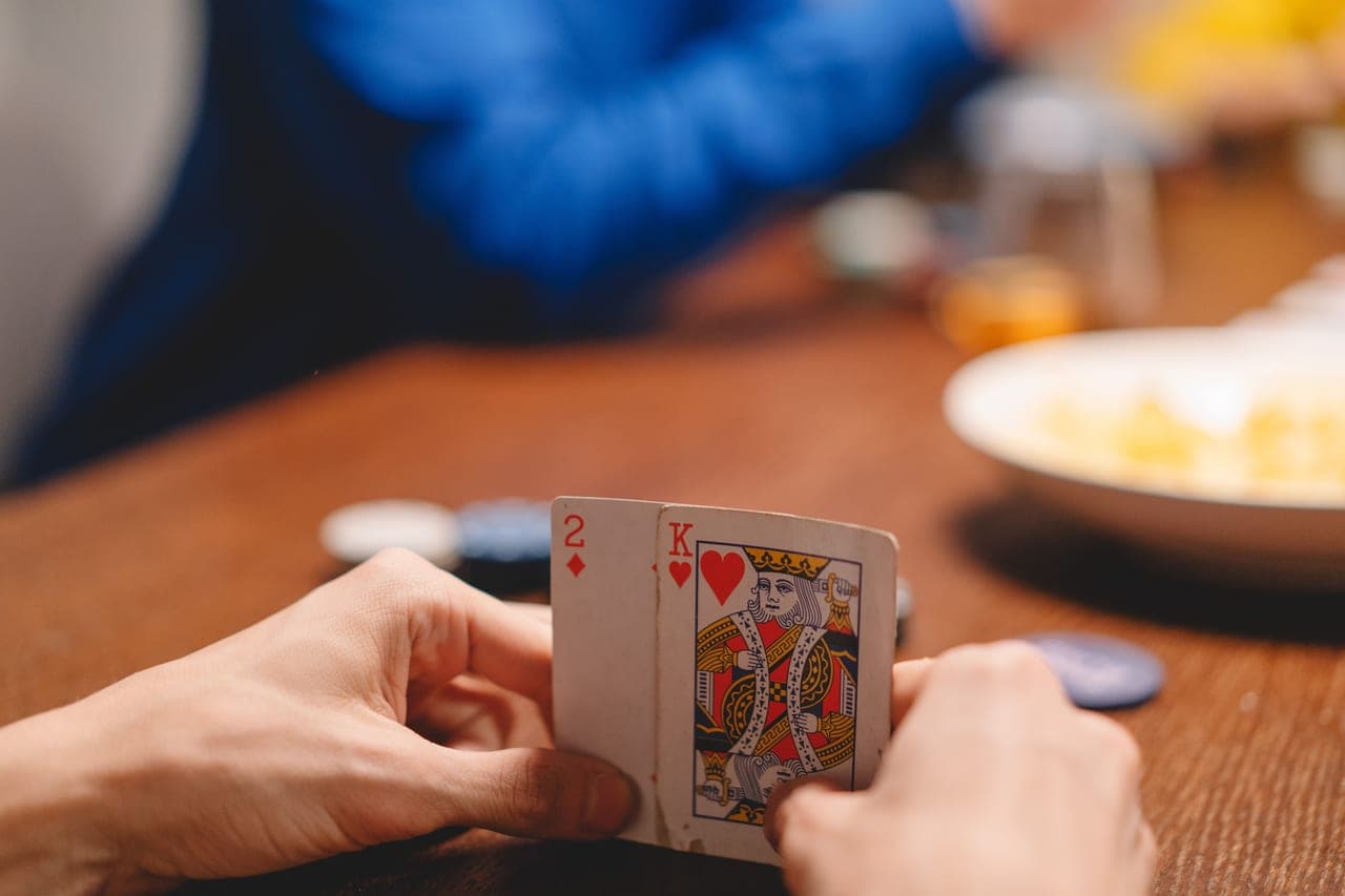 Two people leaning over a small table with cards between them in warm lamplight