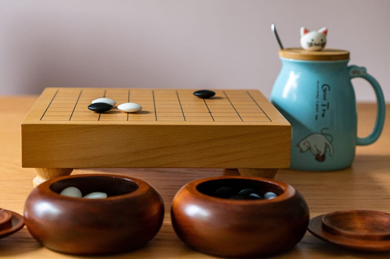 A mid-sized board game box beside a mug on a wooden table
