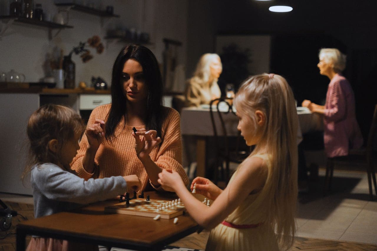 Three generations of a family laughing together over a game at a kitchen table